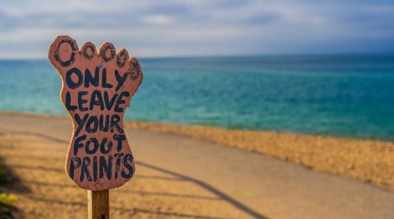 Schild in Fußform am Strand mit der Aufschrift: "Only leave your footprints"