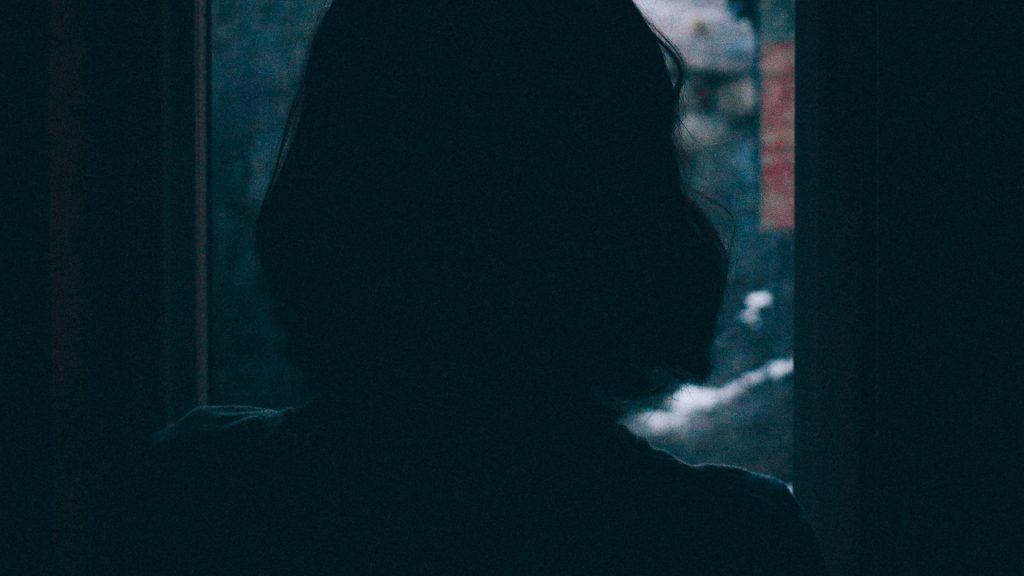 Silhouette einer Frau, die vor einem Fenster steht