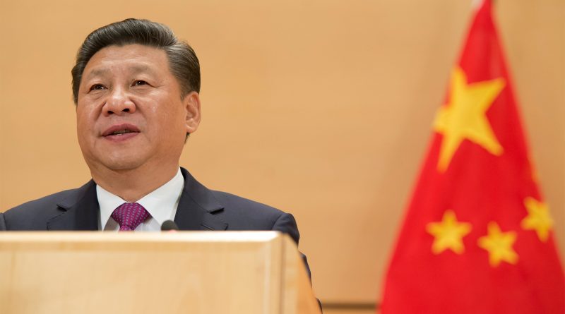 Xi Jinping bei einer Rede im Anzug, daneben die Flagge Chinas