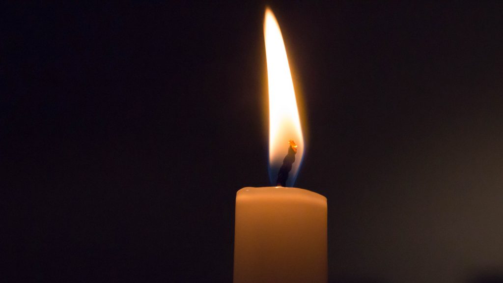 Rote, brennende Kerze in der Dunkelheit