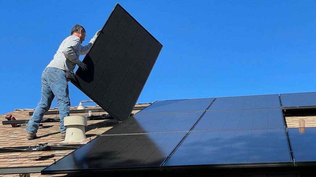 Arbeiter befestigt Solar-Panele auf einem Dach