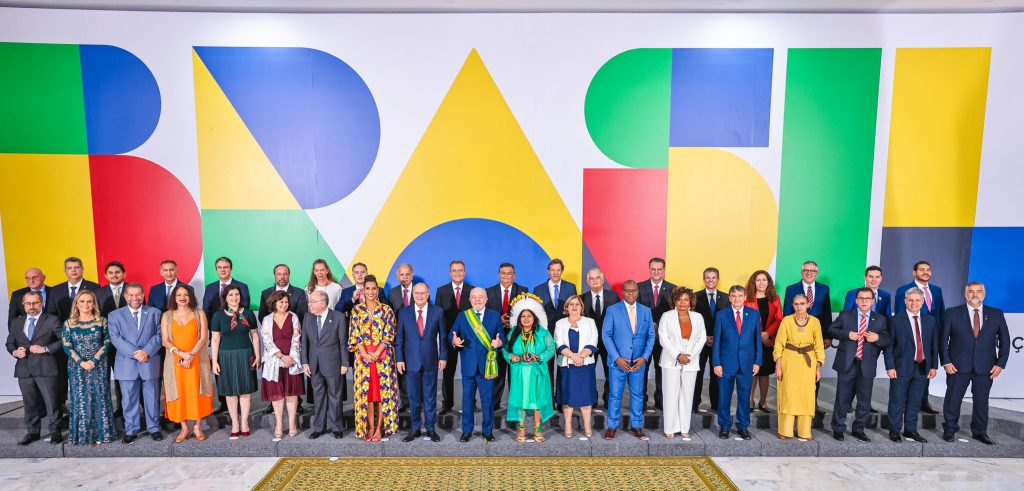 Lula und sein Kabinett vor einer bunten Wand mit der Aufschrift "Brasil"