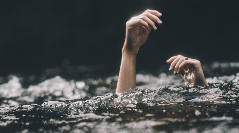 Hände einer Person ragen aus dem Wasser