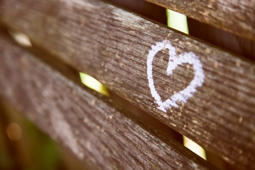 Weißes Herz auf einer braunen Holz-Bank