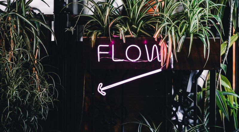 Neon-Schild "Flow" inmitten von Pflanzen