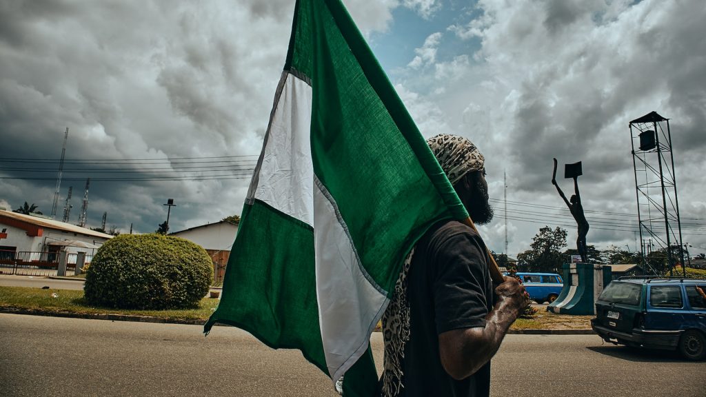 Mann hält nigerianische Flagge am