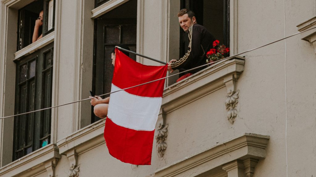 Mann hält peruanische Flagge aus dem Fenster
