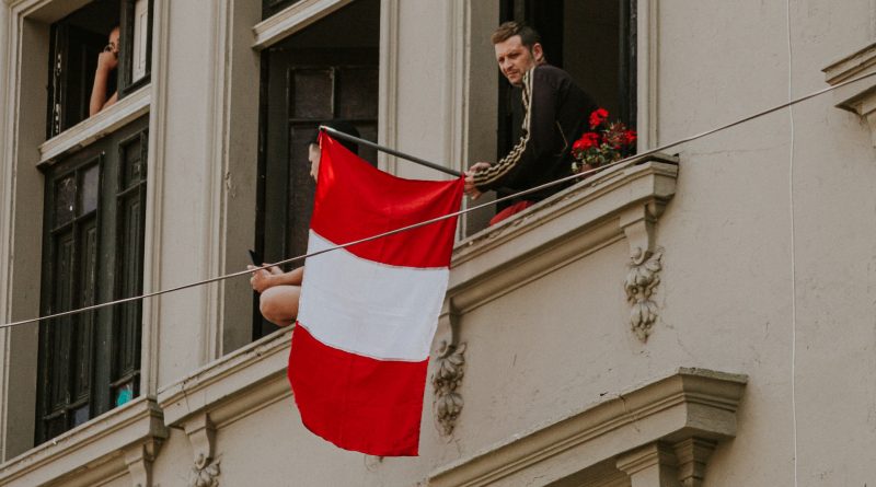 Mann hält peruanische Flagge aus dem Fenster