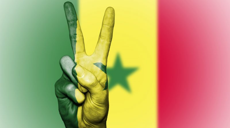 Victory-Zeichen einer Hand vor einer Senegal-Flagge
