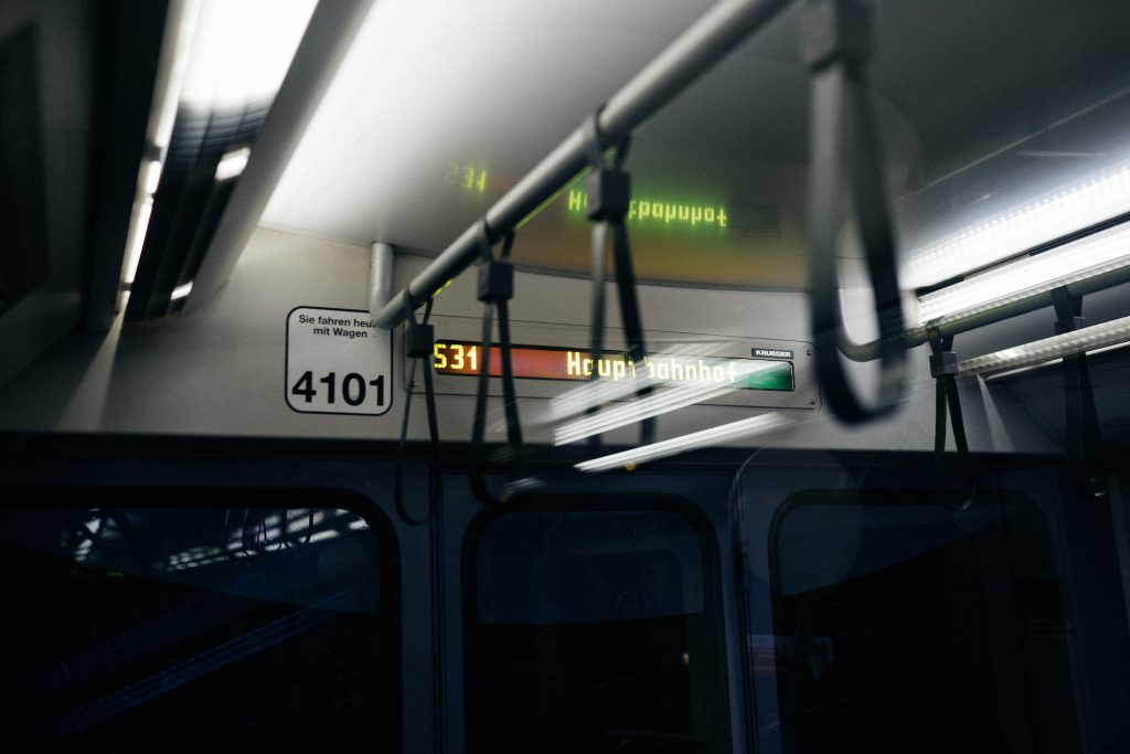 Eine Schnellbahn von innen, dunkel, leuchtende Anzeigetafel mit Schrift "Hauptbahnhof"