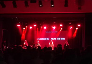Pussy Riot auf der Bühne, rotes Licht, rundherum alles dunkel