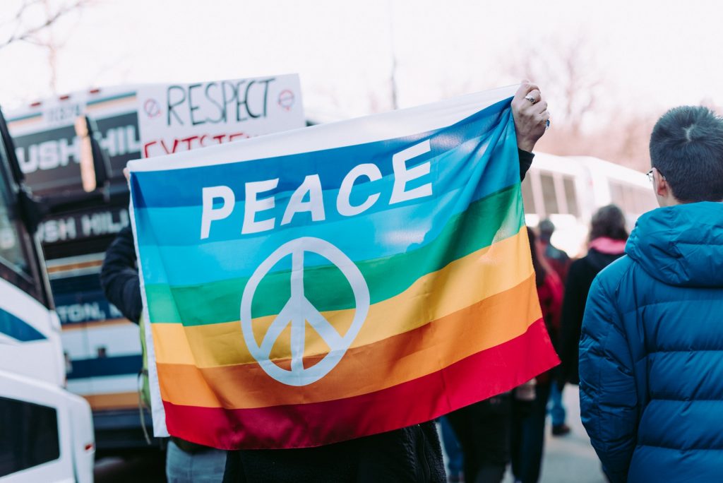 Regenbogenflagge mit Aufschrift PEACE und Peace-Zeichen
