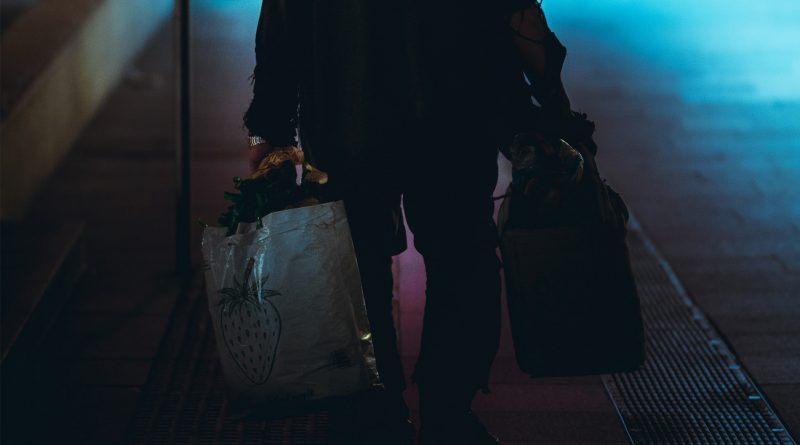 Mann trägt zwei große Taschen in der Dunkelheit