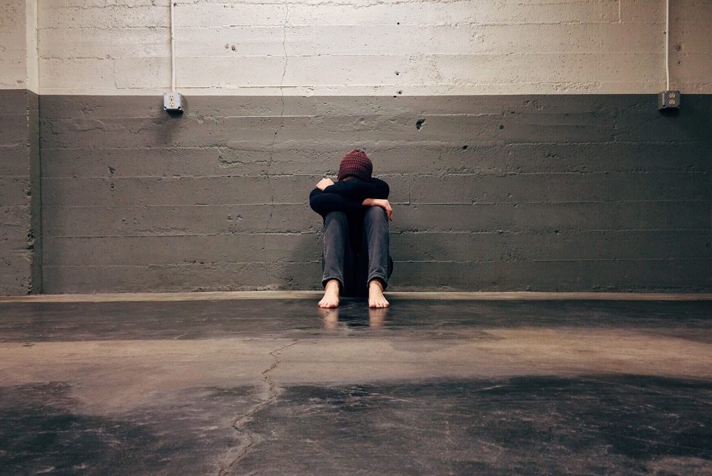 Person in schwarzem Hoodie in einem dunklen Raum