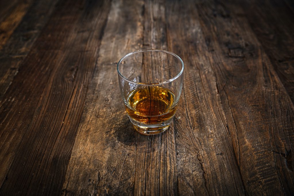 Whiskey-Glas auf einem dunkelbraunen Holztisch