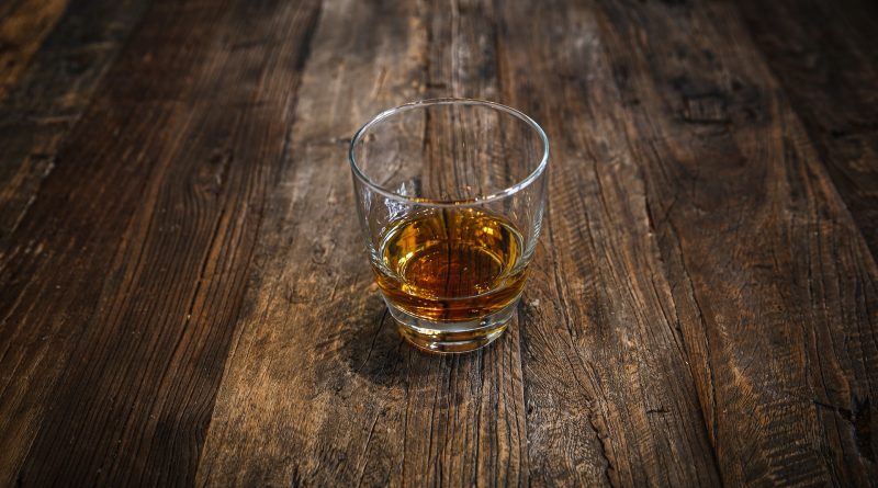 Whiskey-Glas auf einem dunkelbraunen Holztisch