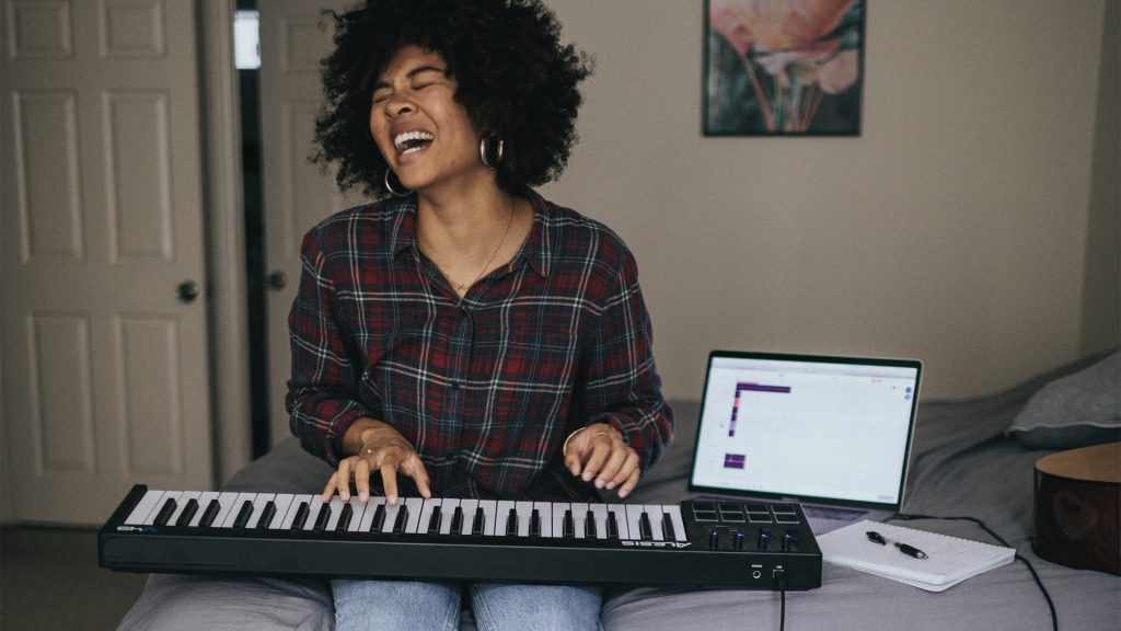 Frau sitzt am Bett mit Klavier und singt