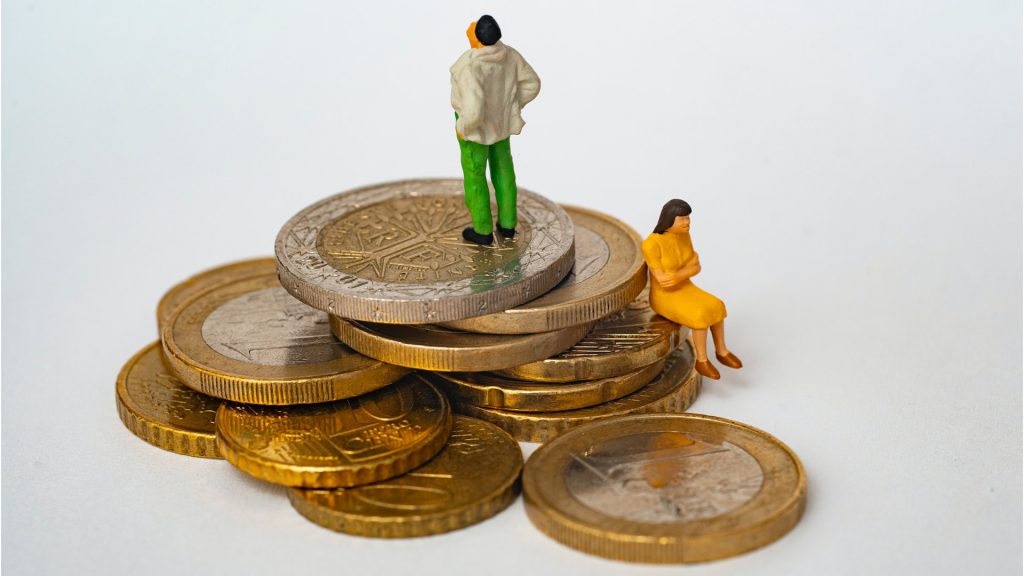 Männliche Figure steht auf Stapel Geldmünzen, weibliche Figur sitzt eine Stufe weiter unten