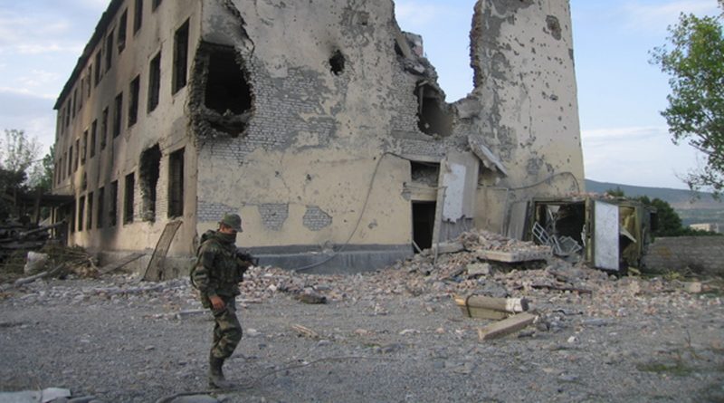 Russischer Soldat in Georgien vor zerstörtem Gebäude