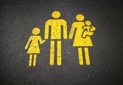 Gelbe Strichfiguren-Familie (Vater, Mutter, zwei Kinder) auf Asphalt gemalt