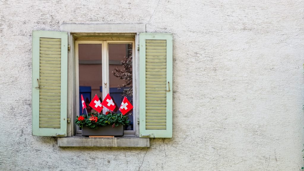 Fenster, in dem drei kleine Schweizer Fahnen stehen