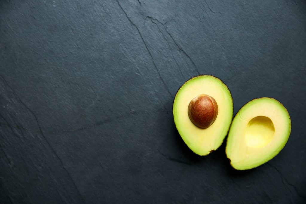 Zwei Avocado-Hälfte liegen auf einer schwarzen Fläche