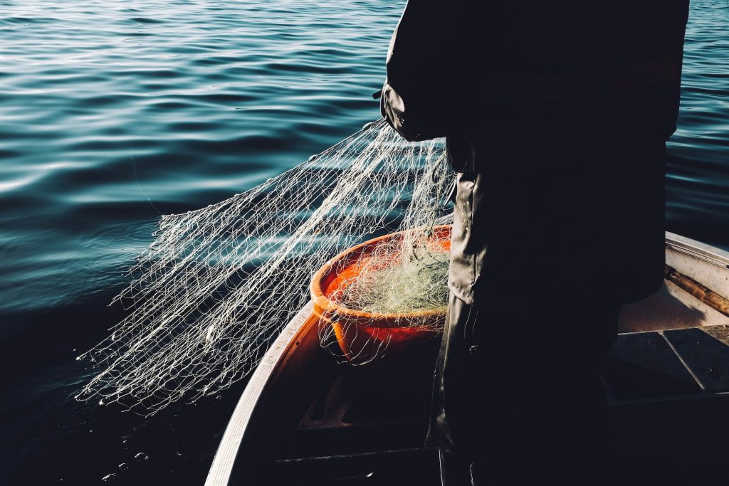 Silhouette eines Fischers auf dem Wasser, der sein Netz einholt