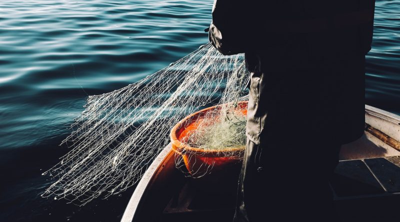 Silhouette eines Fischers auf dem Wasser, der sein Netz einholt