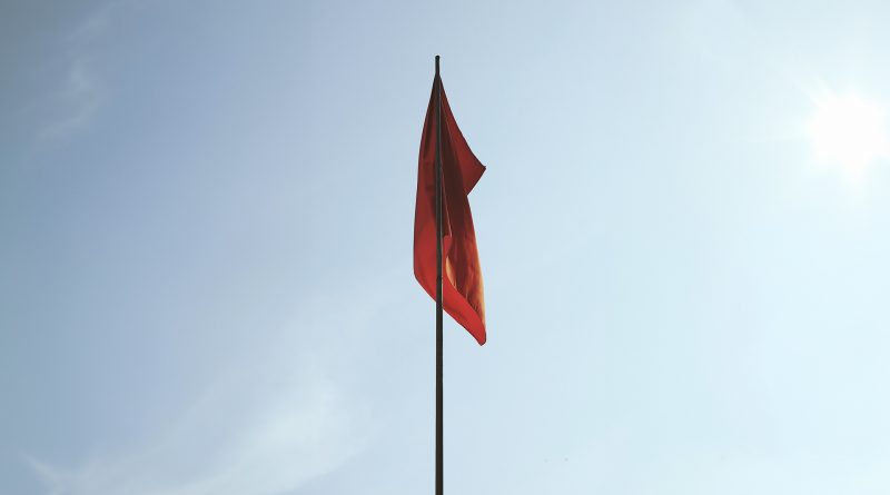 Rote Flagge, die schlaff an einem Master herunterhängt