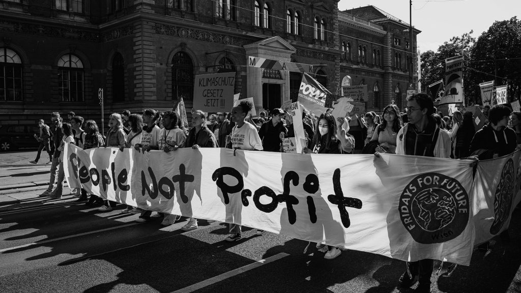 Menschen bei Fridays For Future Demo halten Banner "People not Profit", schwarz-weiß Bild