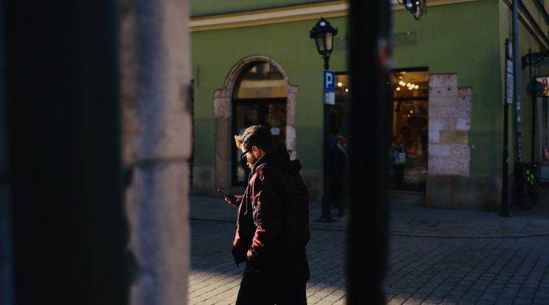 Mann geht auf der Straße mit einem Handy in der Hand