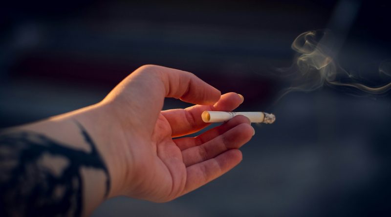 Foto einer Hand, die eine rauchende Zigarette hält