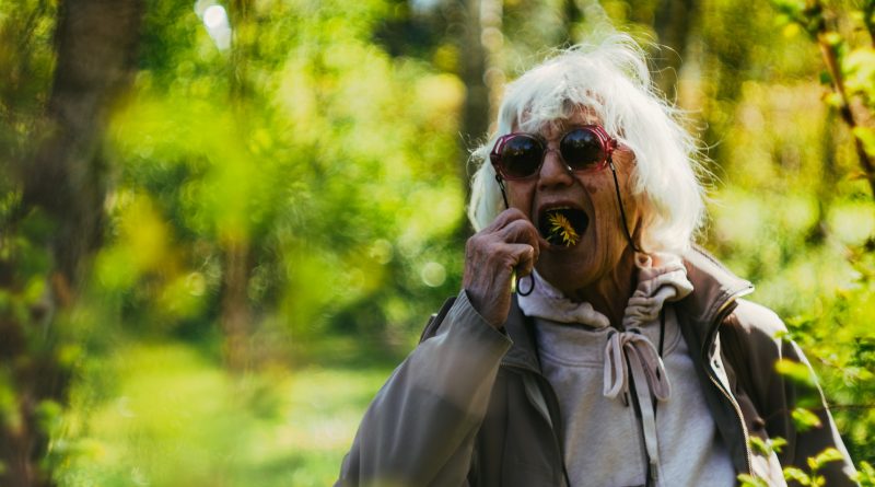 Ältere Frau isst eine Blume im Wald