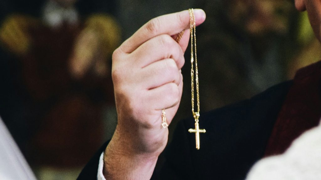 Pfarrer hält eine Kreuzkette in der Hand