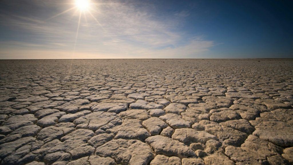 Trockener, rissiger Boden bei blauem Himmel und Sonnenschein
