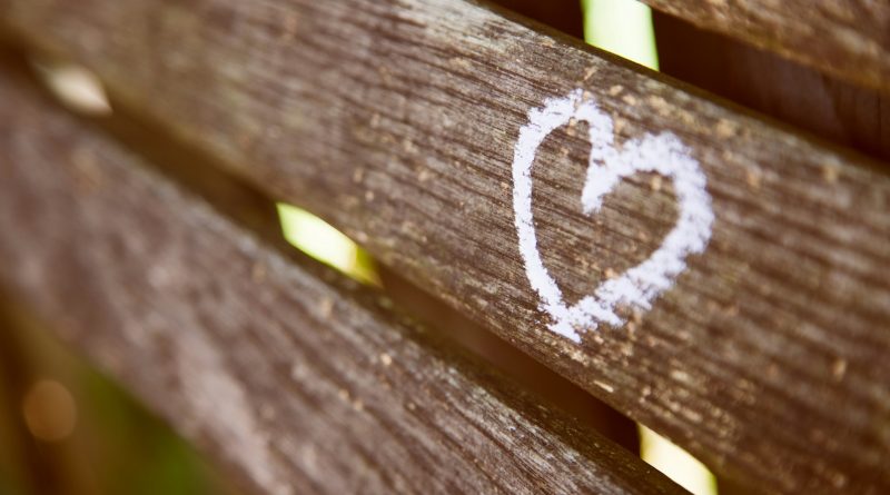 Ein weißes Herz gemalt auf eine Holzbank.
