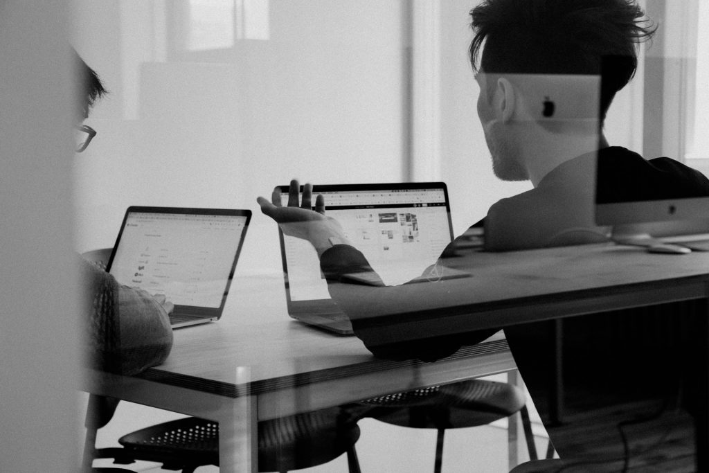 Zwei junge Personen sitzen vor ihren Laptops, schwarz-weiß-Bild