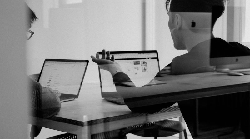 Zwei junge Personen sitzen vor ihren Laptops, schwarz-weiß-Bild