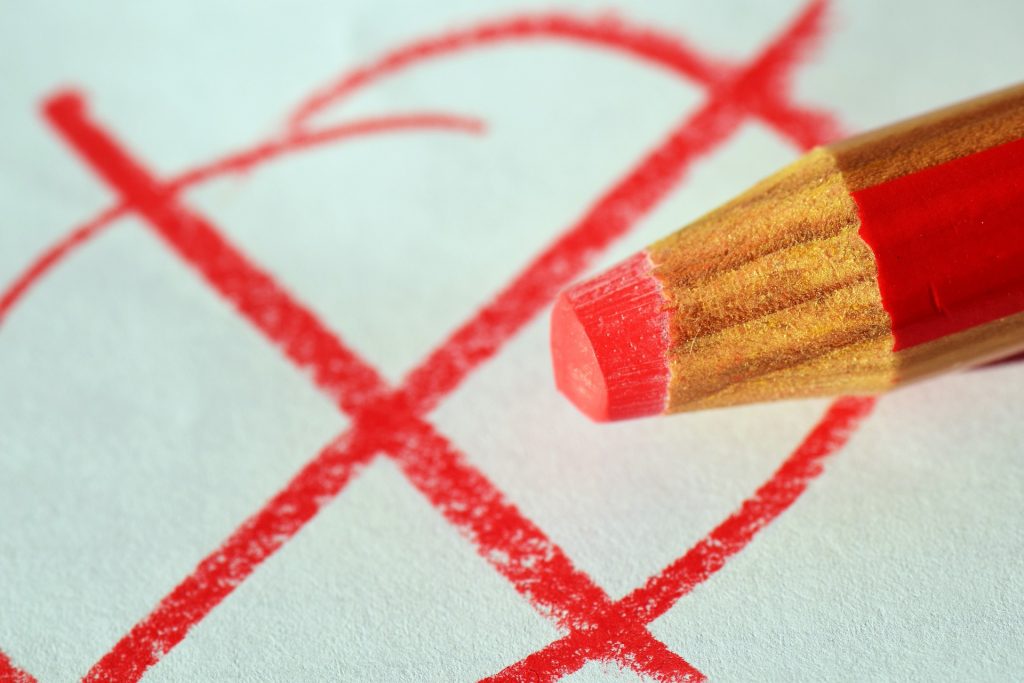 Roter Stift, der ein Kreuz in einen Kreis malt