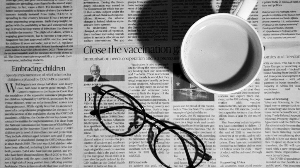 Auf einer gedruckten Zeitung liegt einer schwarze Brille und steht eine weiße Kaffee-Tasse