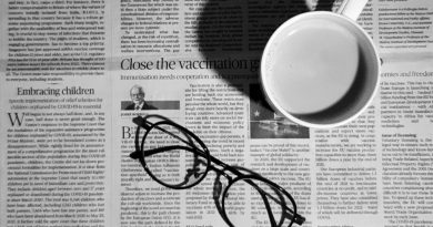 Auf einer gedruckten Zeitung liegt einer schwarze Brille und steht eine weiße Kaffee-Tasse