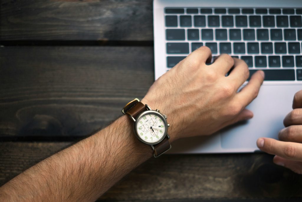 Eine Arm mit Uhr am Handgelenk auf einer Laptoptastatur
